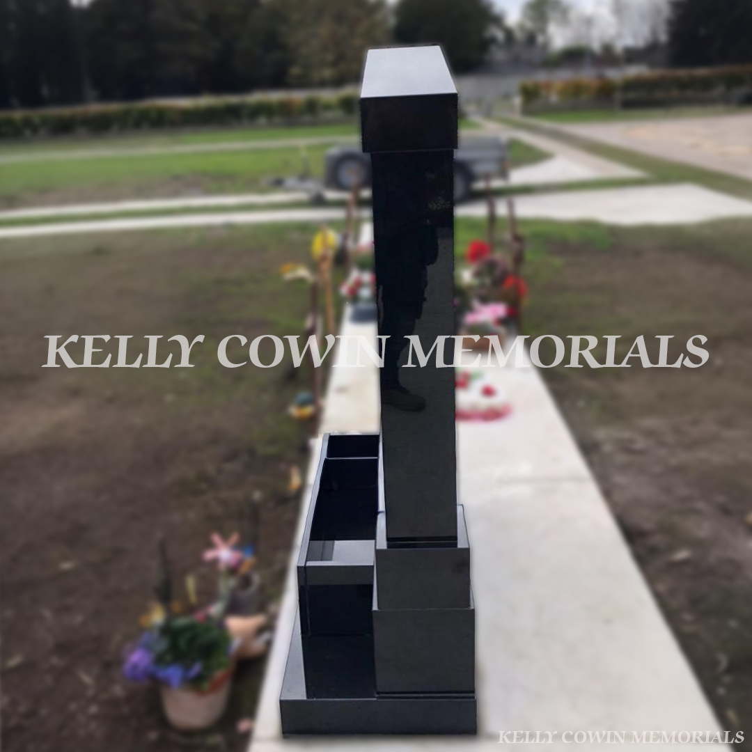 Side view of a Black granite butterfly children’s headstone with a cap and pillars and coloured inscription in Balgriffin Cemetery Dublin