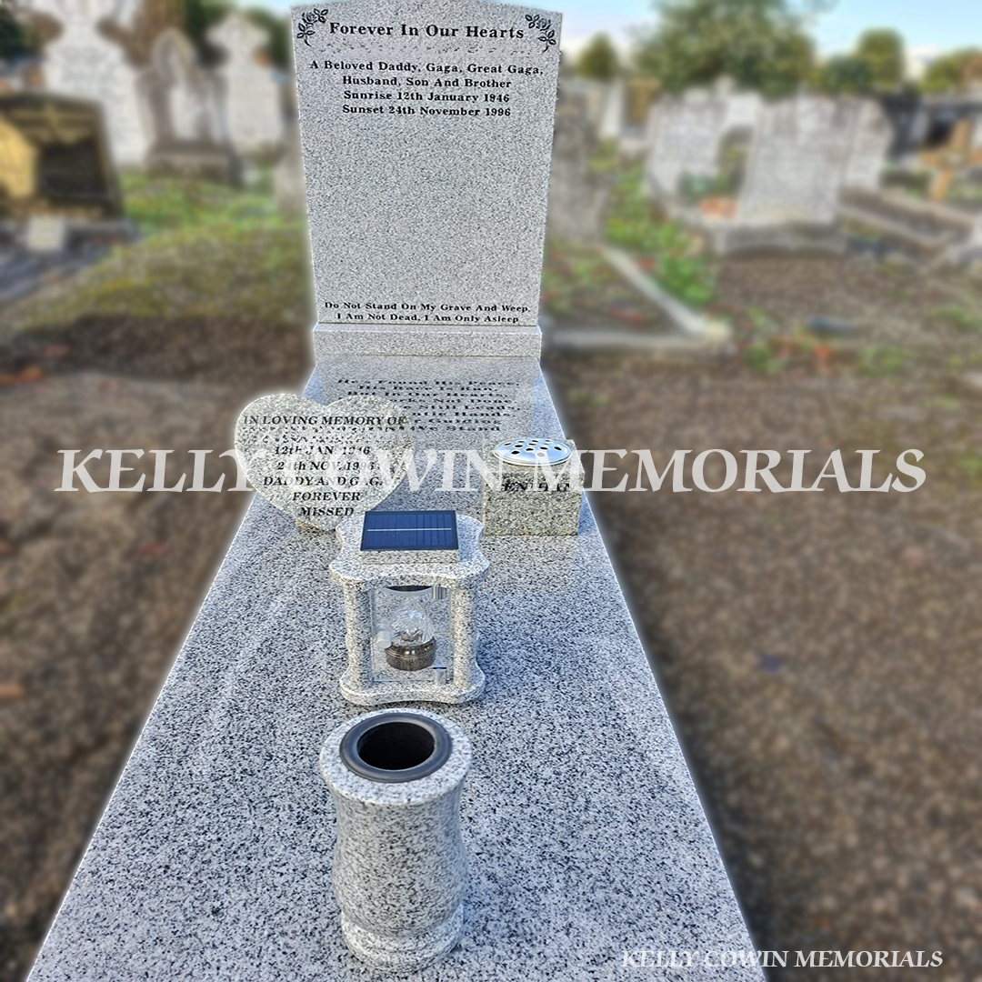 Close-up of grey granite accessories including tall vase, solar lantern with eternal light, square vase and heart.