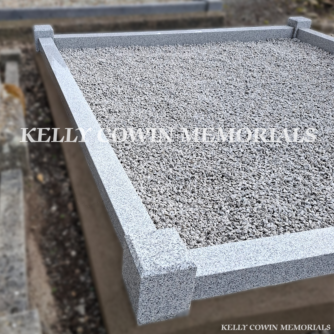 Side close up view of grey granite memorial with kerbing and corner posts