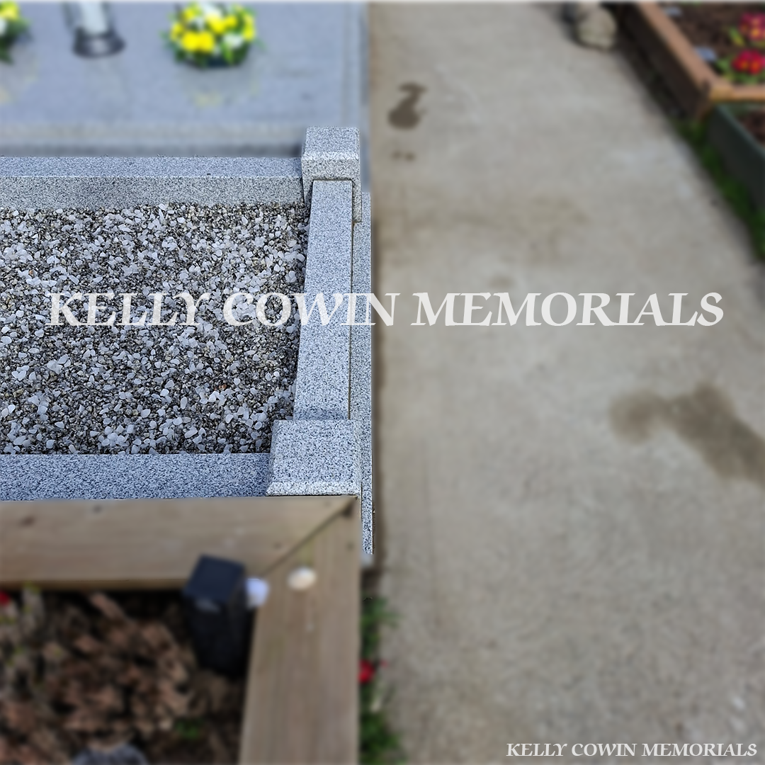 Side view of grey granite memorial with kerbing and mixed chippings
