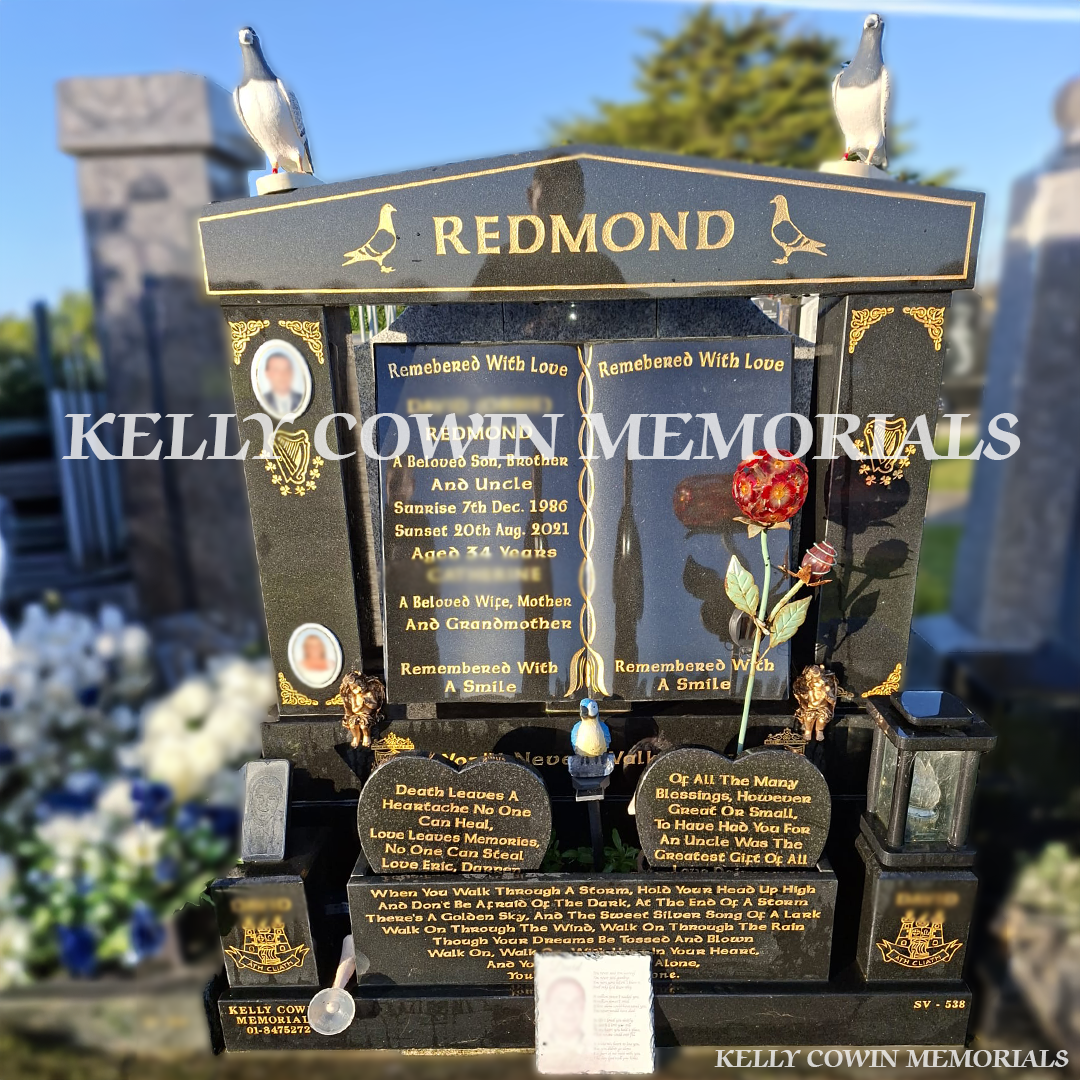 Front view of black granite book headstone with gold inscription, pigeon statues and oval ceramic photographs in Dardistown Cemetery Dublin
