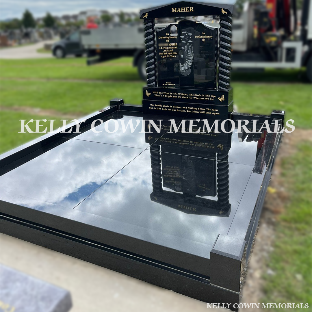 Side view of black granite memorial with twisted pillars and full kerbing