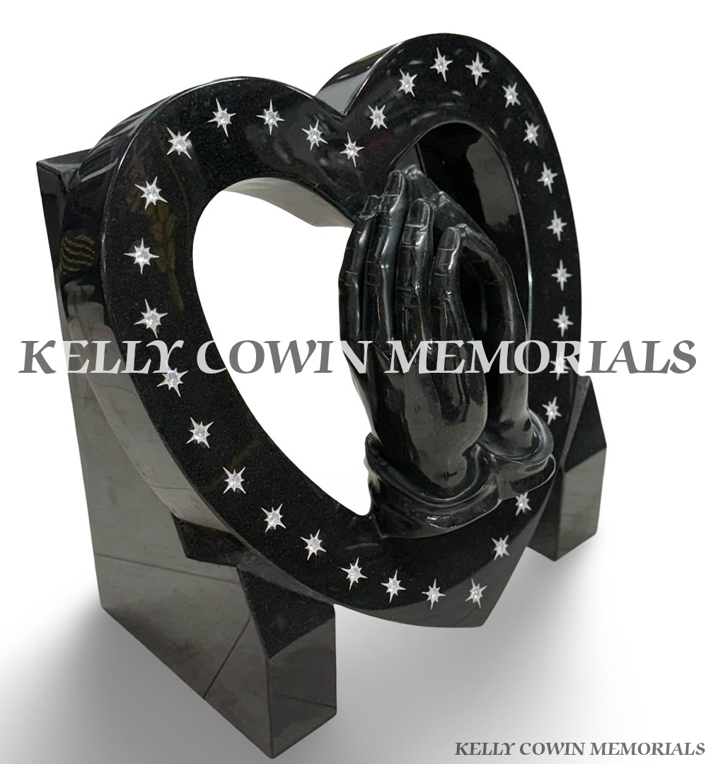 Side view of polished black granite heart memorial featuring praying hands and silver star engraving.