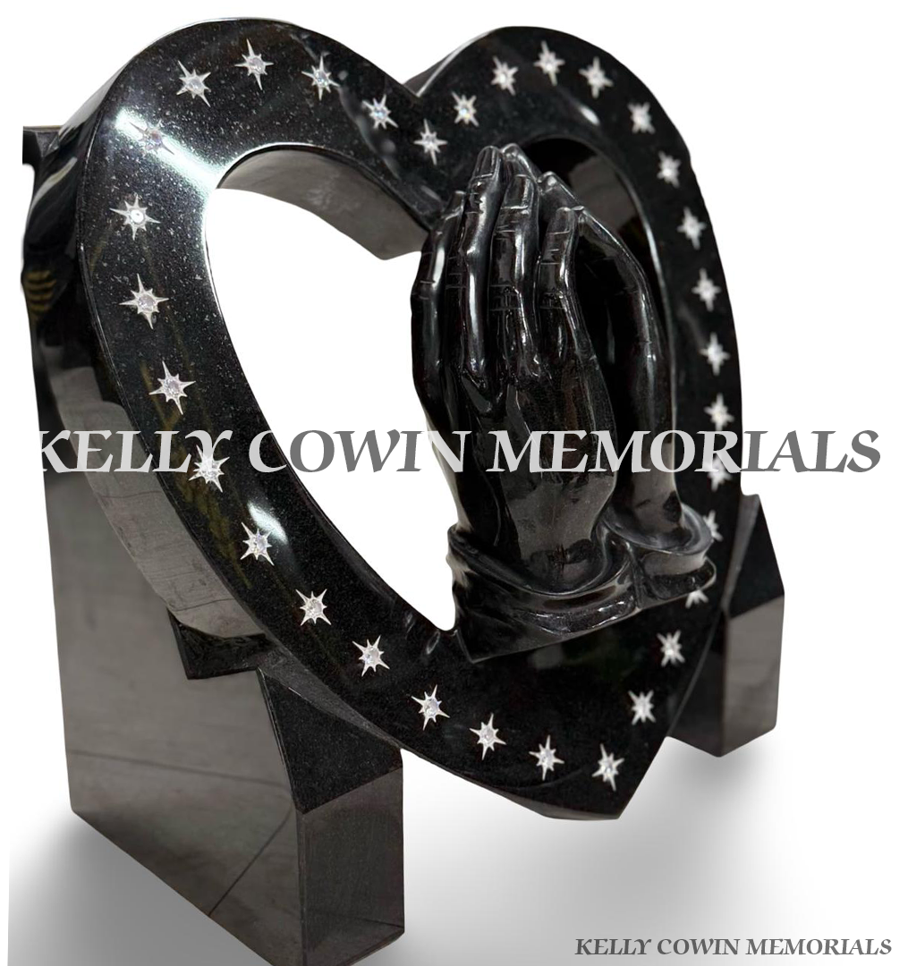 Custom black granite open heart memorial with sculpted praying hands and silver engraved star details.