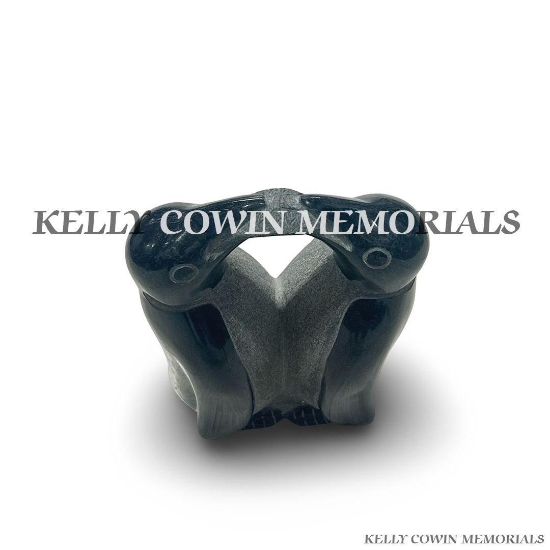 Close-up of penguins sharing a fish carved into black granite memorial