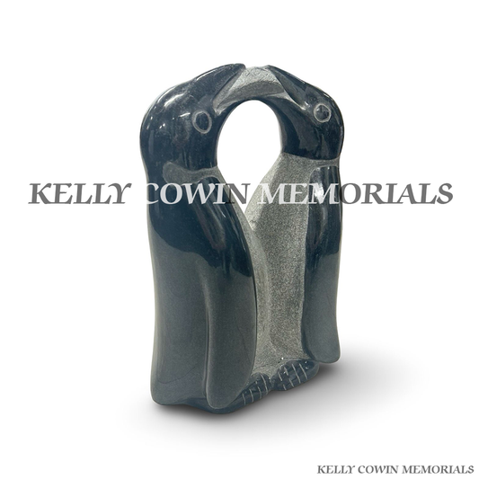 Front view of black granite penguin memorial statue with two penguins