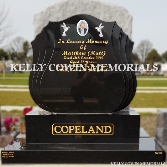 Front view close up of black granite shell shaped headstone with gold inscription in Balgriffin Cemetery