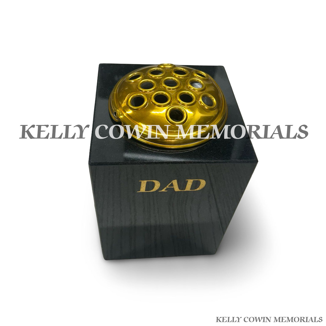 Close-up of gold engraving and gold lid on black granite vase