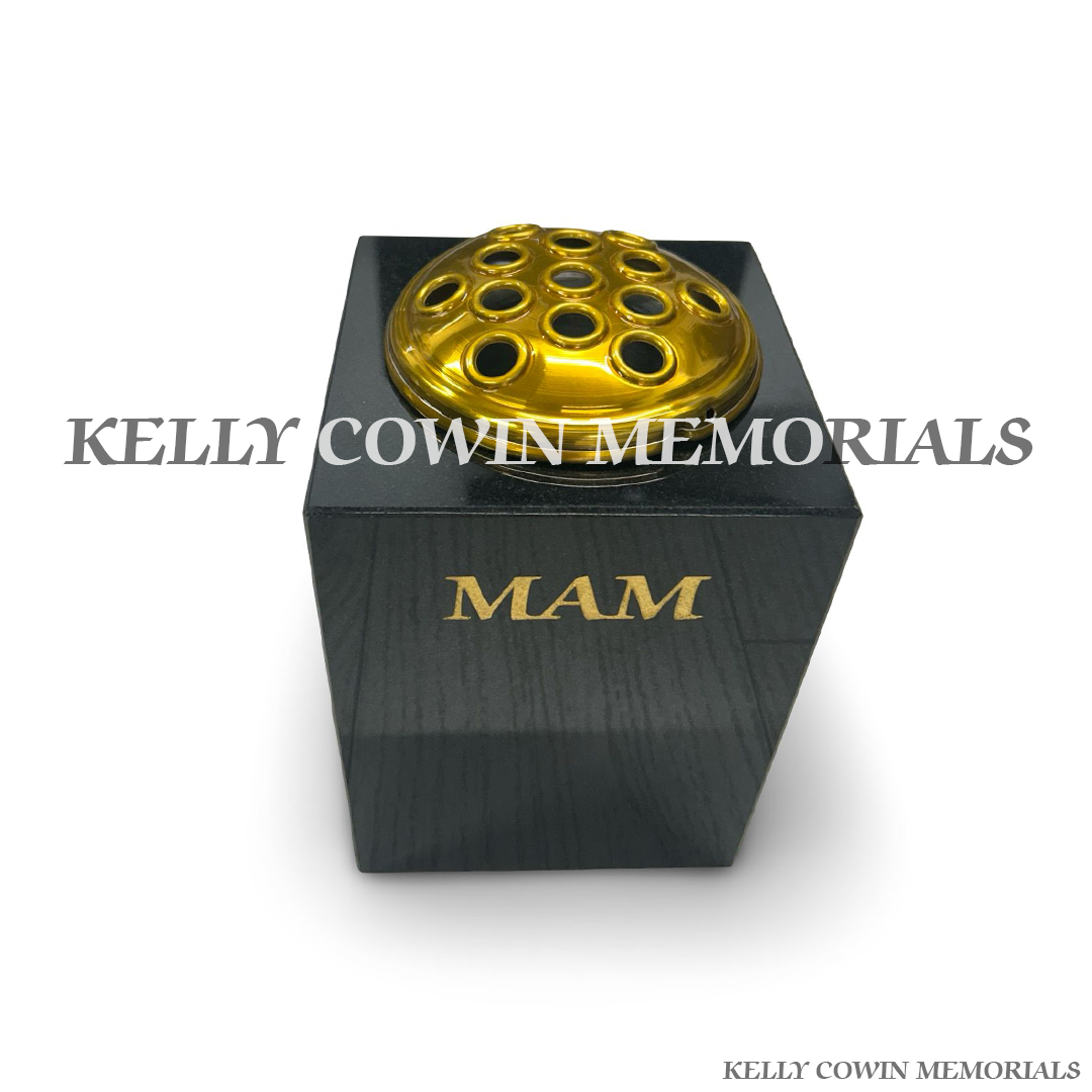 Close-up of gold Mam inscription on black granite vase