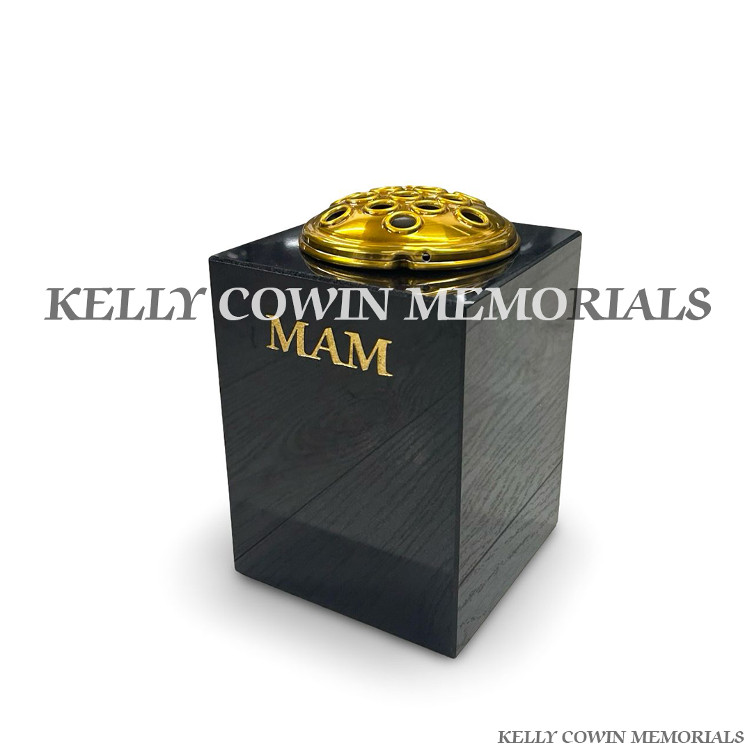 Side view of polished black granite square vase with gold lid
