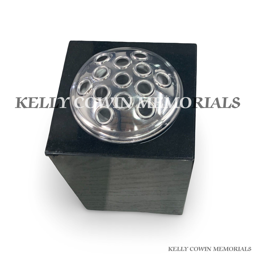 Close-up of silver lid on black granite square vase