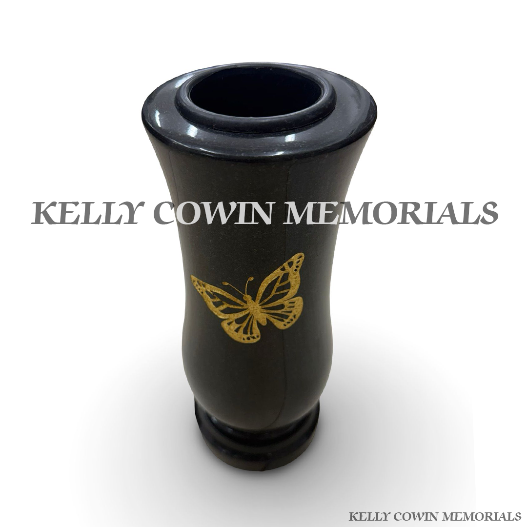 Close-up of gold lettering and butterfly engraving on black granite vase