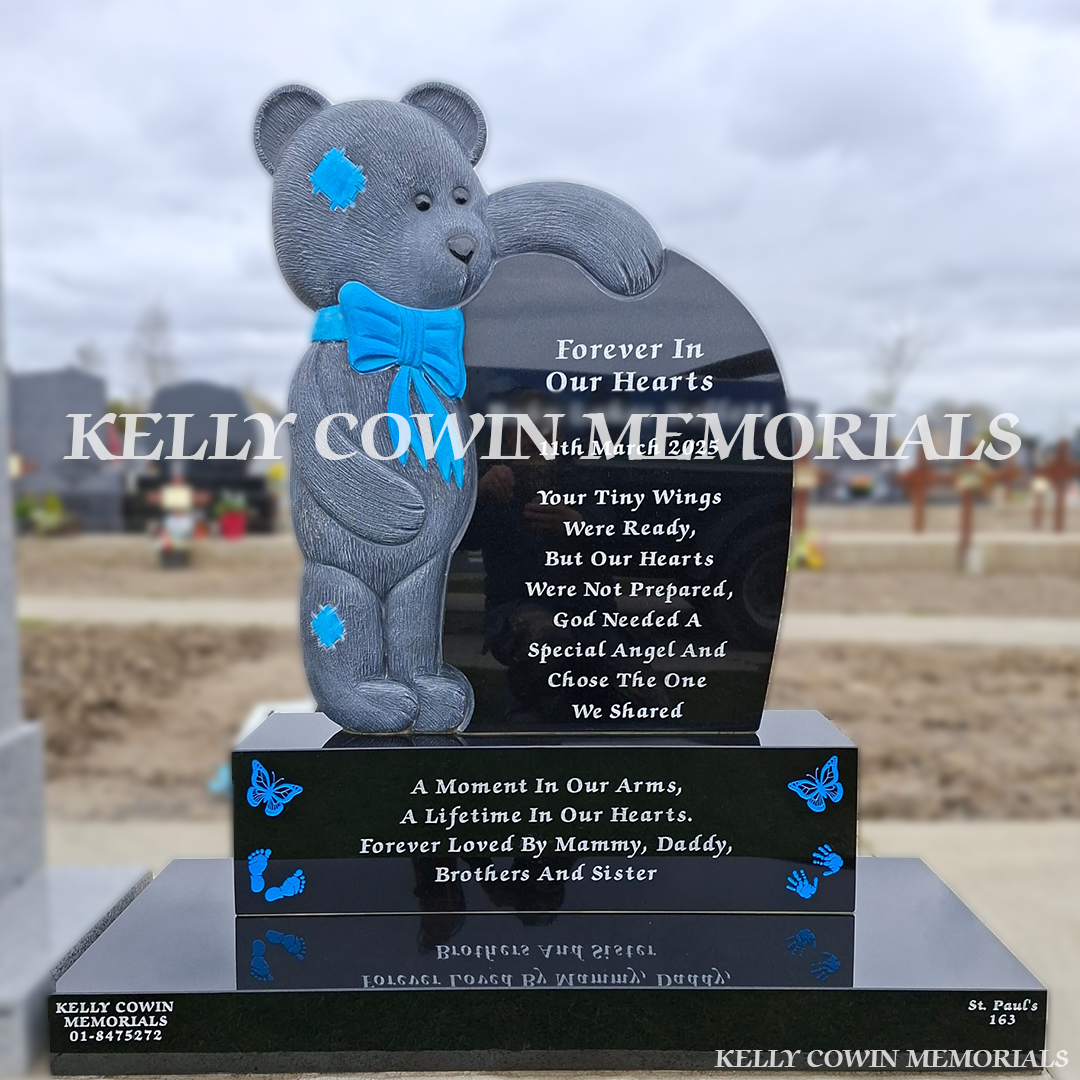 Front view of black granite teddy bear children’s headstone with blue detailing in Balgriffin Cemetery