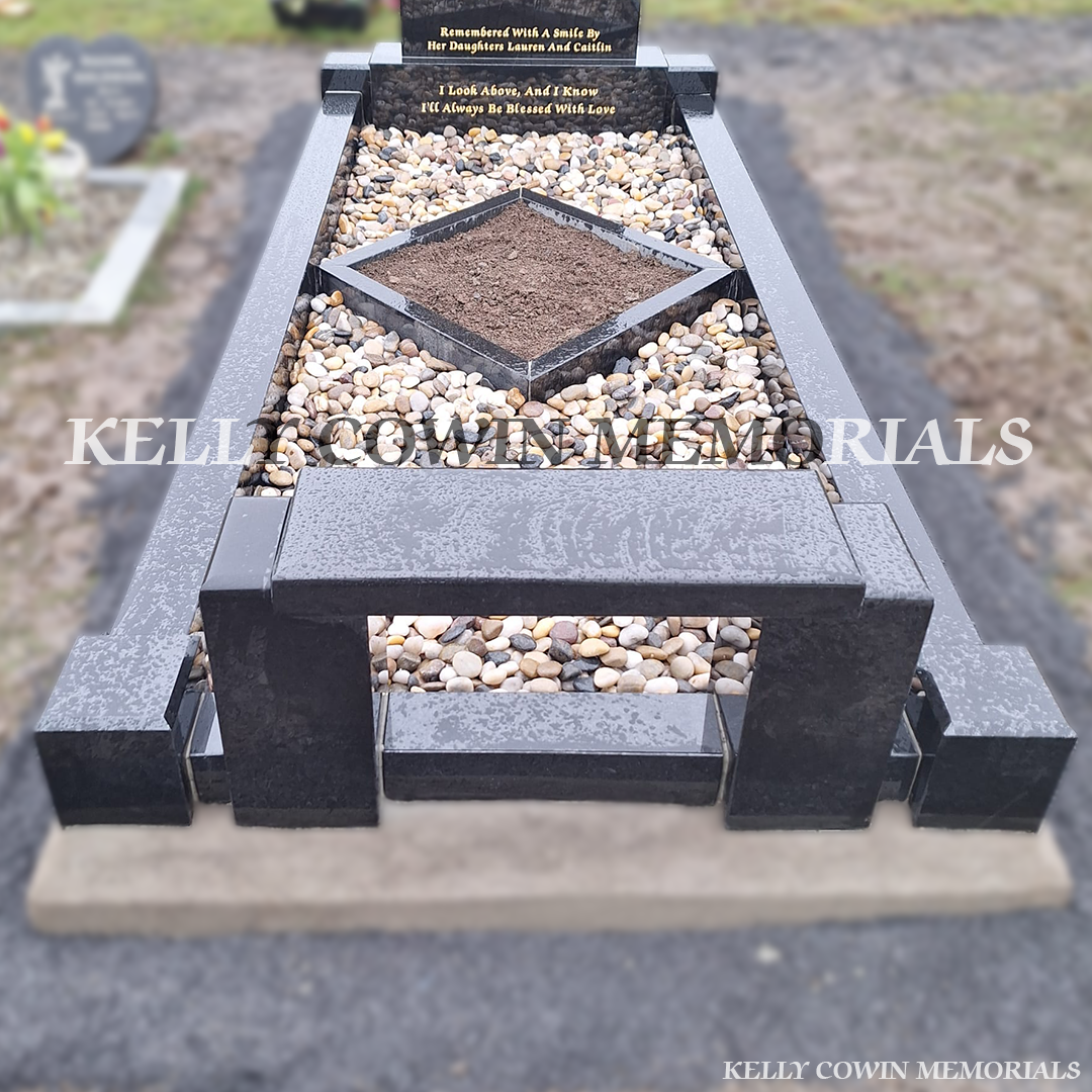 front view of black granite memorial with kerbing, garden area and bench