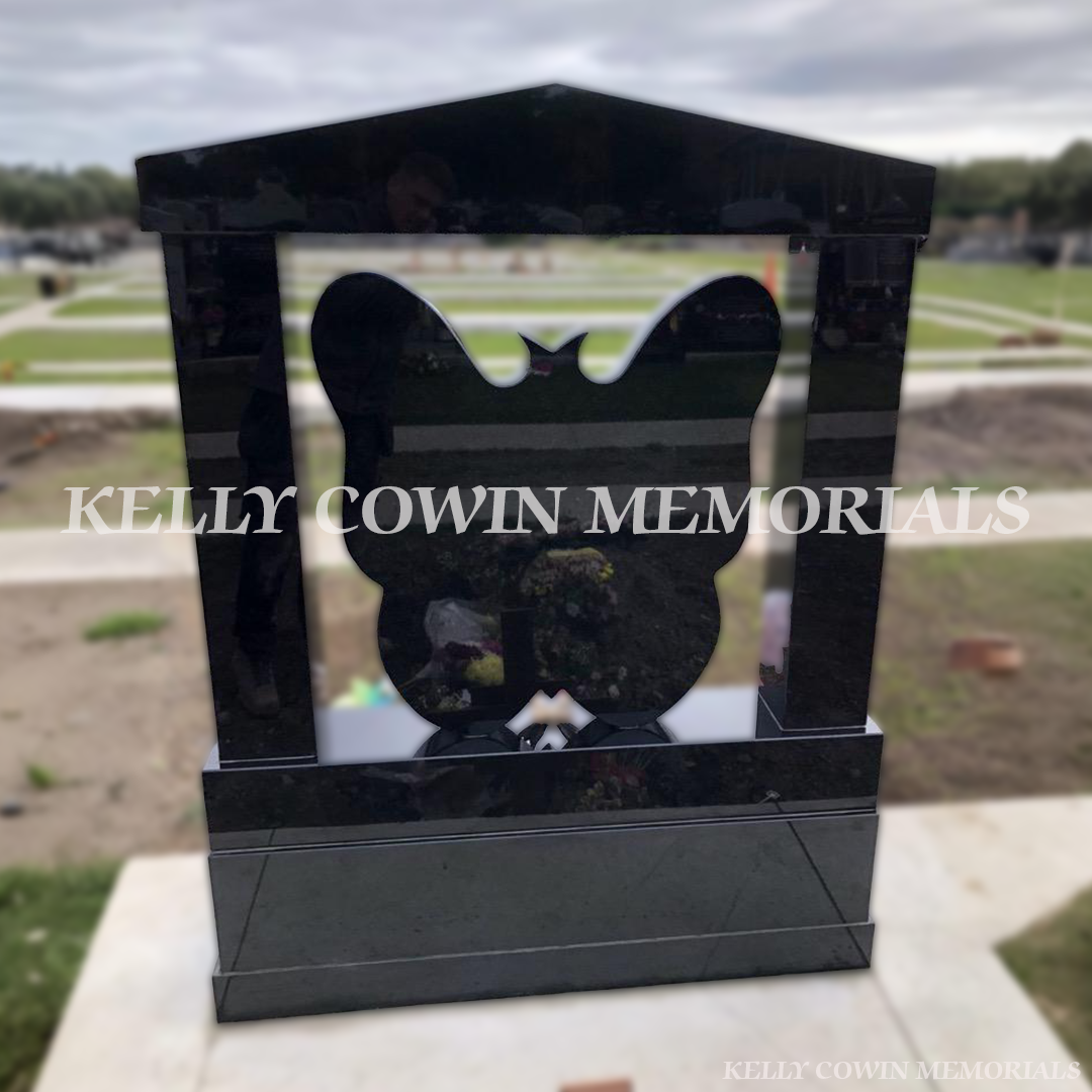 Back view of a Black granite butterfly children’s headstone with cap and pillars and coloured inscription in Balgriffin Cemetery Dublin