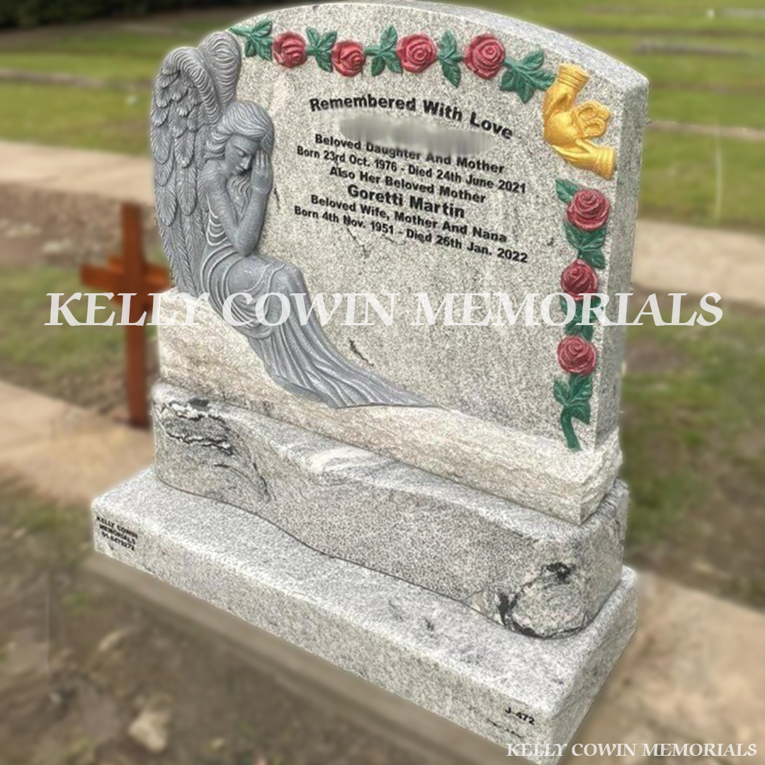 Front view of custom grey granite angel boulder headstone with carved roses and Claddagh in a Dublin cemetery