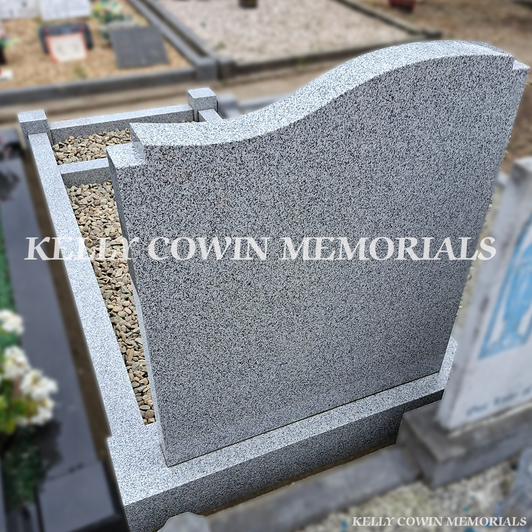 back view Grey granite custom headstone with granite kerbing, mixed pebble garden border, granite corner posts and black inscription in St. Peter and Paul's Cemetery, Balbriggan.