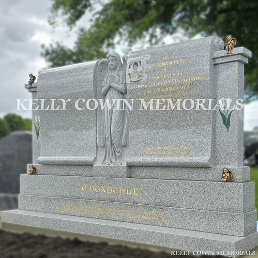 Pearl white double scroll Traveller headstone with carved angel, bronze angels and gold leaf inscription in Mount St Oliver’s Cemetery, Limerick