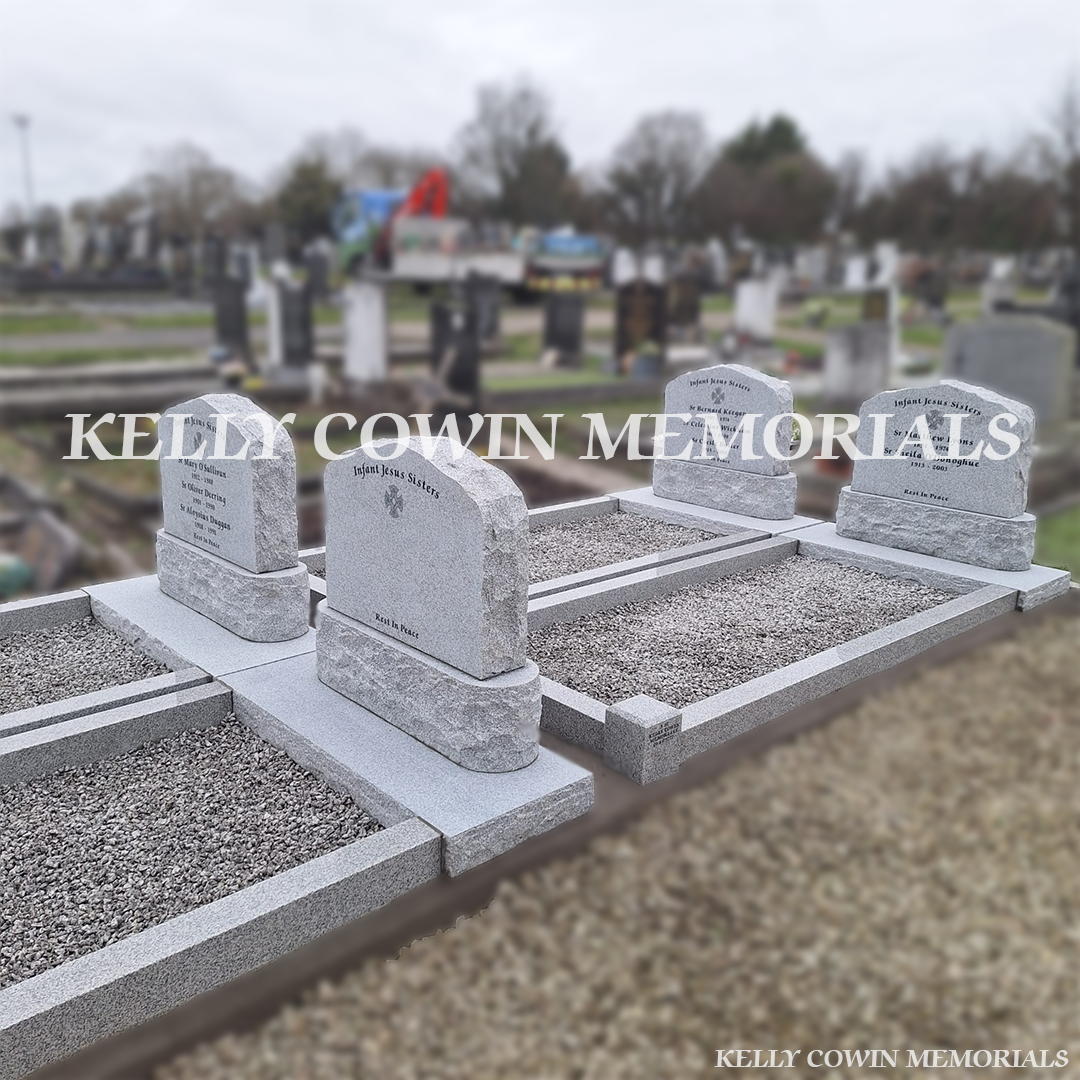 Front view of four grey granite boulder headstones with black inscription and new kerbing
