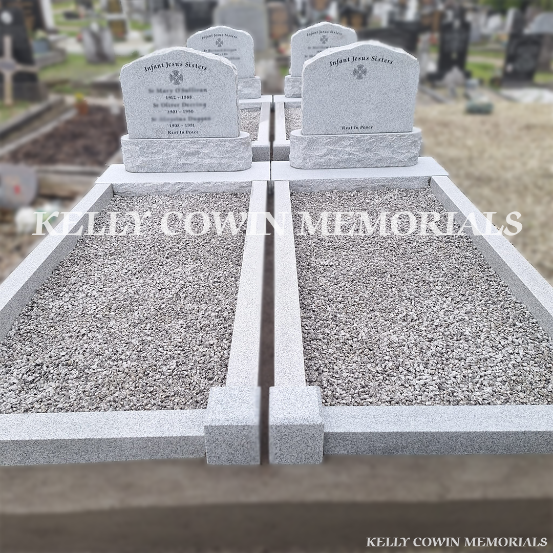 Front view of four grey granite boulder headstones with black inscription and new kerbing