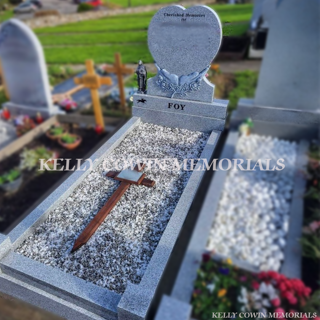 Grey granite antique carved hands holding heart-shaped memorial headstone with kerbing and chippings by Kelly Cowin Memorials Ireland