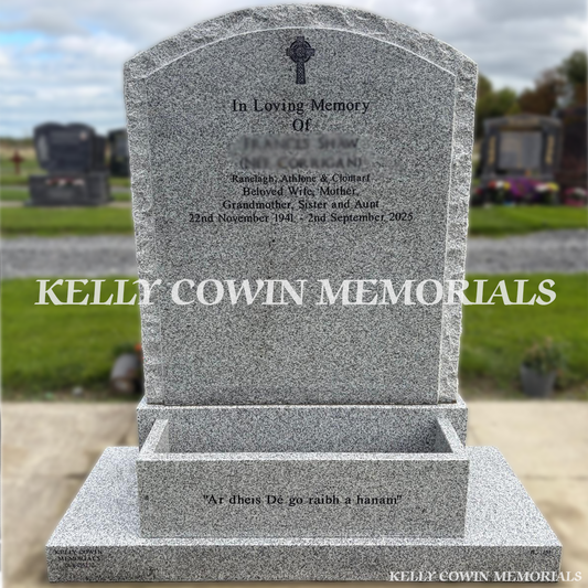 Grey granite rough boulder headstone with natural textured edges, curved top, black inscription, Celtic cross engraving, matching granite base, plinth and flowerbox, erected in Dardistown Cemetery, Dublin, by Kelly Cowin Memorials.