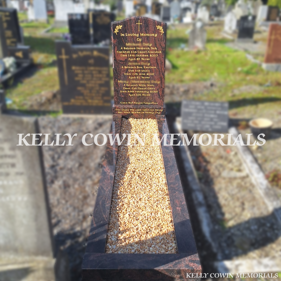 Pandora granite OG headstone with natural red and black granite patterns, gold engraved inscription, cross and floral details, matching granite base, full grave kerbing and Yellow Seena decorative chippings in Glasnevin Cemetery, Dublin, by Kelly Cowin Memorials.