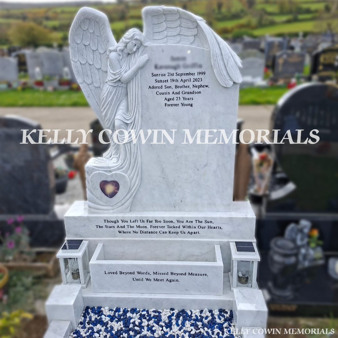 Close-up of angel carving and black inscription on white marble headstone